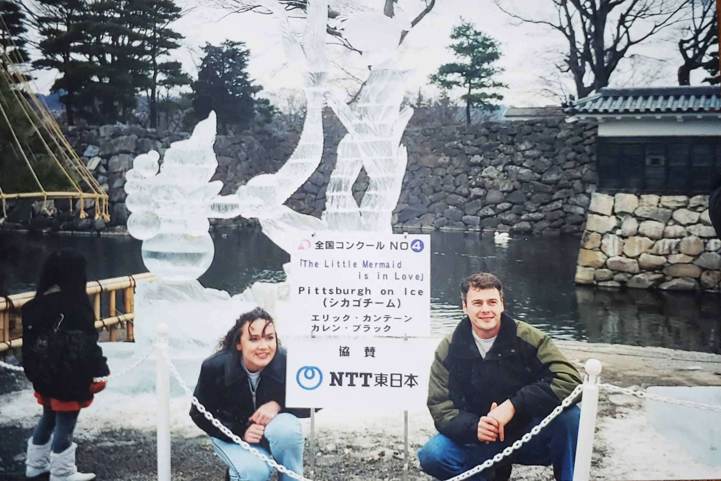 Two ice sculptors crouching beside their carved ice sculpture, The Little Mermaid is in Love, at a competition in Matsumoto, Japan