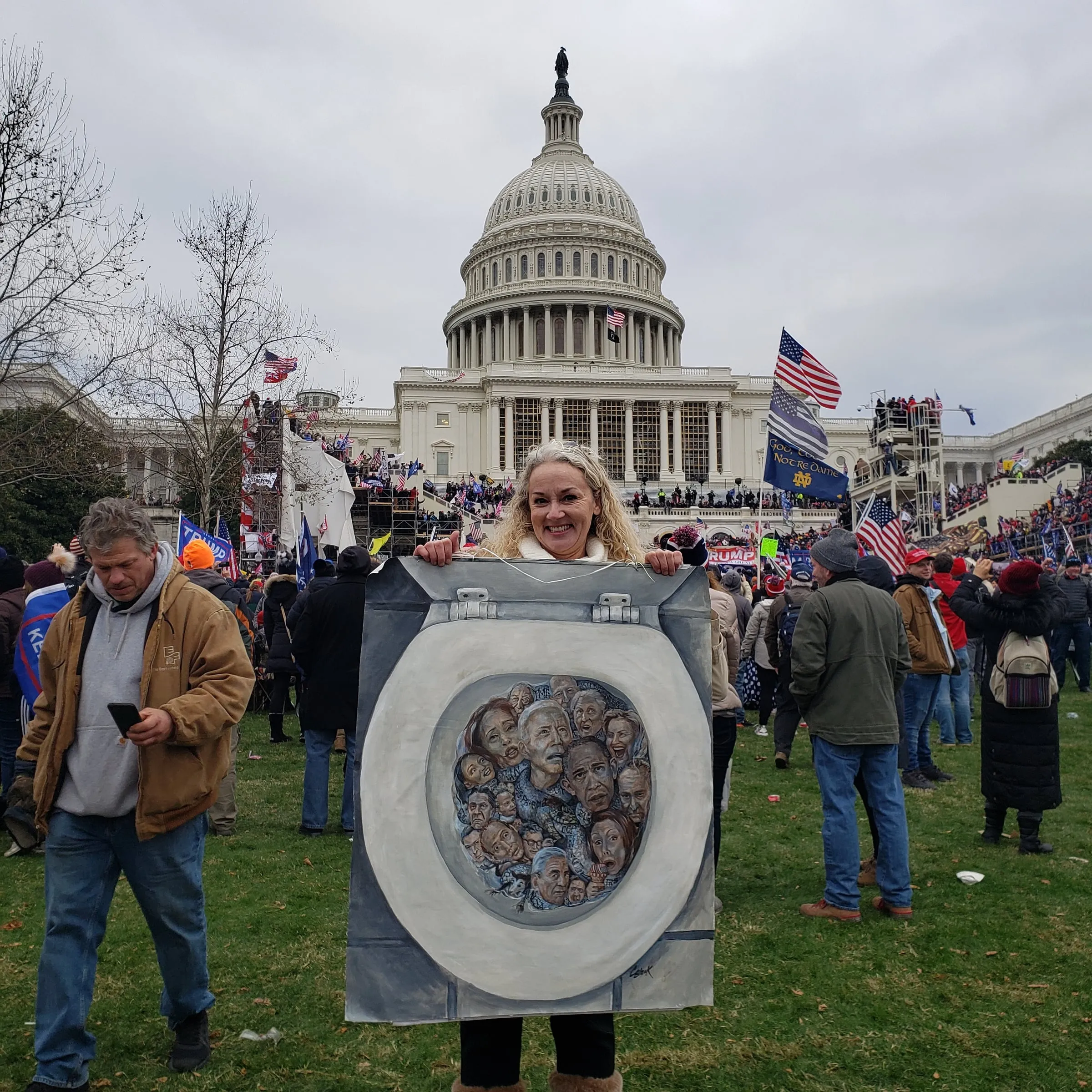 Woman holding the painting Royal Flush, a toilet seat filled with faces, in front of the U.S. Capitol