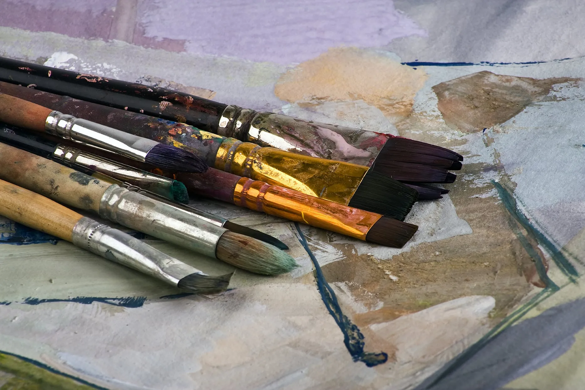 Paintbrushes resting on a paint-smeared palette
